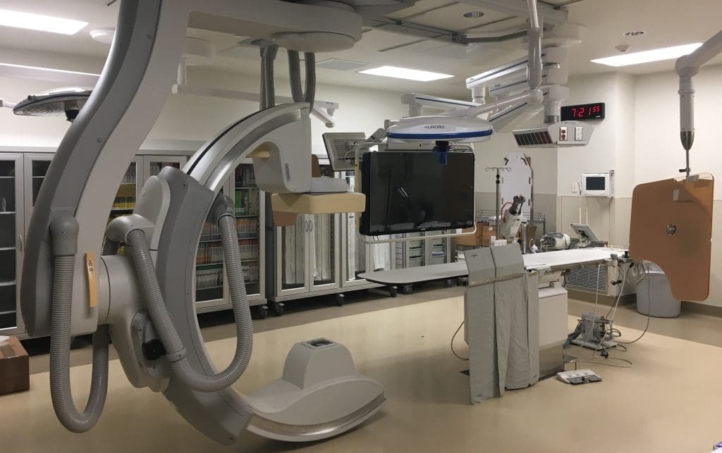 A modern hospital room with advanced medical imaging equipment, monitors, and storage cabinets, ready for patient procedures.