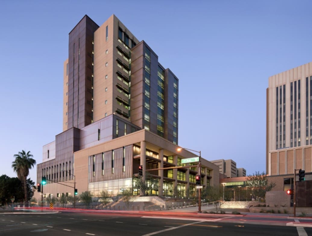 A modern multi-story courthouse building with large glass windows, viewed at dusk from across the street at an urban intersection.